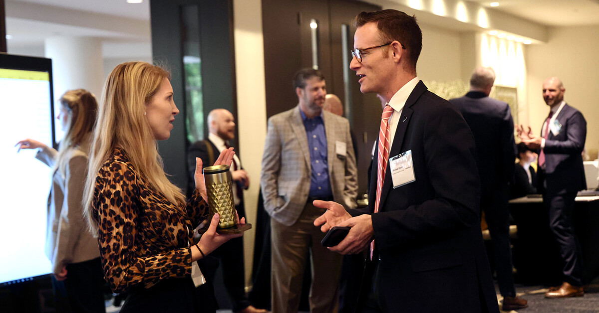 Networking. Michael Galvin (right), Accenture Federal Services managing director, speaks with a fellow attendee at the 2026 Artificial Intelligence Summit.